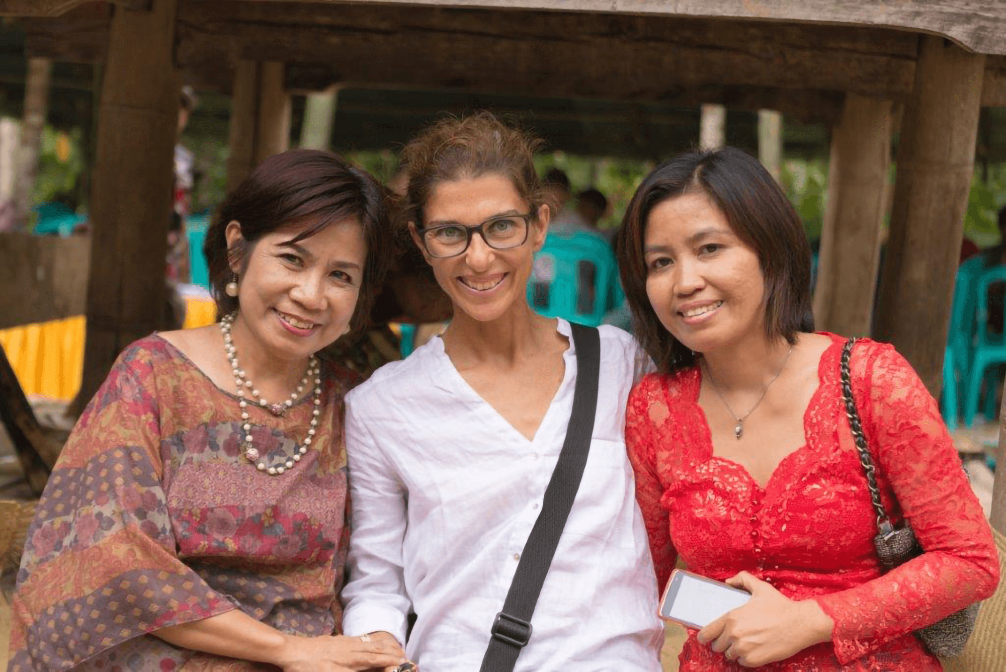 Three multiracial middle-aged women standing together and smiling.